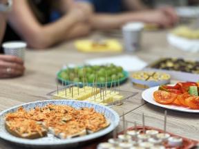 a table full of finger food and snacks with people around it
