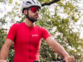 A man in a cycling helmet and red ADA Tour de Cure cycling shirt looking into the distance
