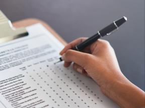 hand filling out a form on a clipboard